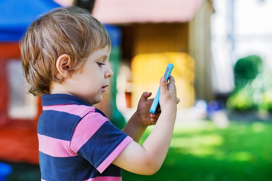 Young boy taking picture outside using smartphone camera