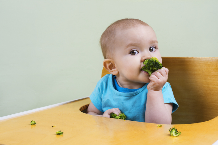 Beautiful baby eating broccoli