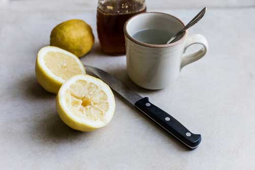 taza de agua con limón en rodajas al lado