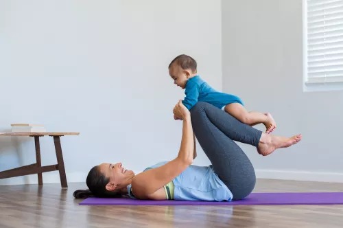 New Mother Does Yoga On A Mat While Nursing Child by Stocksy Contributor  McKinsey Jordan - Stocksy